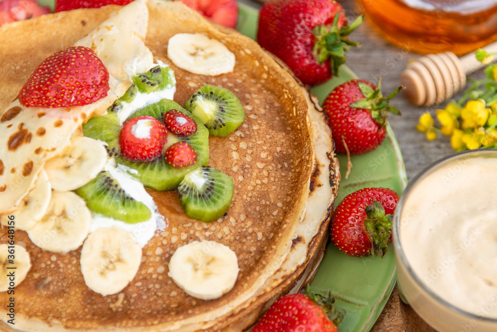 Pancakes with strawberries, kiwi, honey and banana for summer Breakfast.  Children's pancake Breakfast.