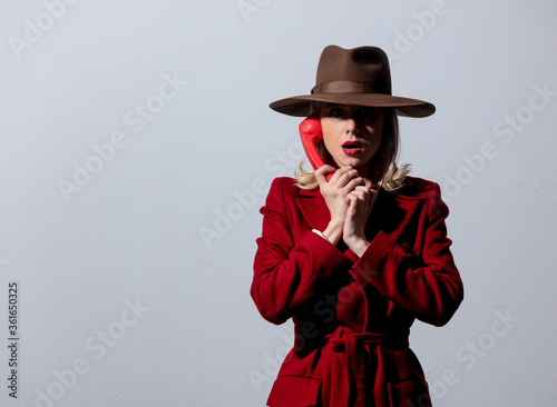Blonde girl in red coat and vintage hat with dial handset
