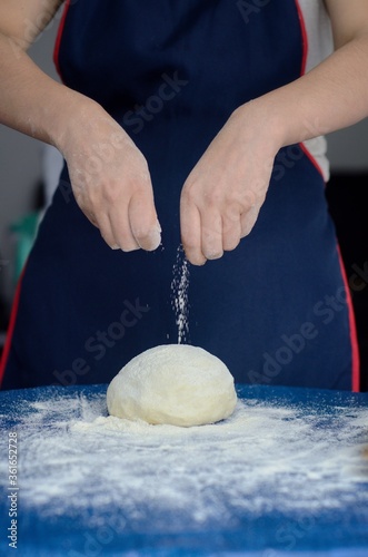 Pastelero prepara la masa y arroja harina en el aire. Manos de panadero con harina y masa para hornear. photo