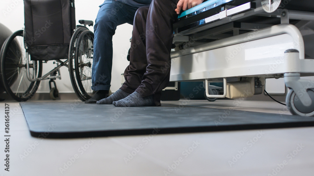 Physiotherapist exercising with disabled person using wheelchair on a therapy table. Physiotherapist exercising with disabled person using wheelchair on a therapy table.