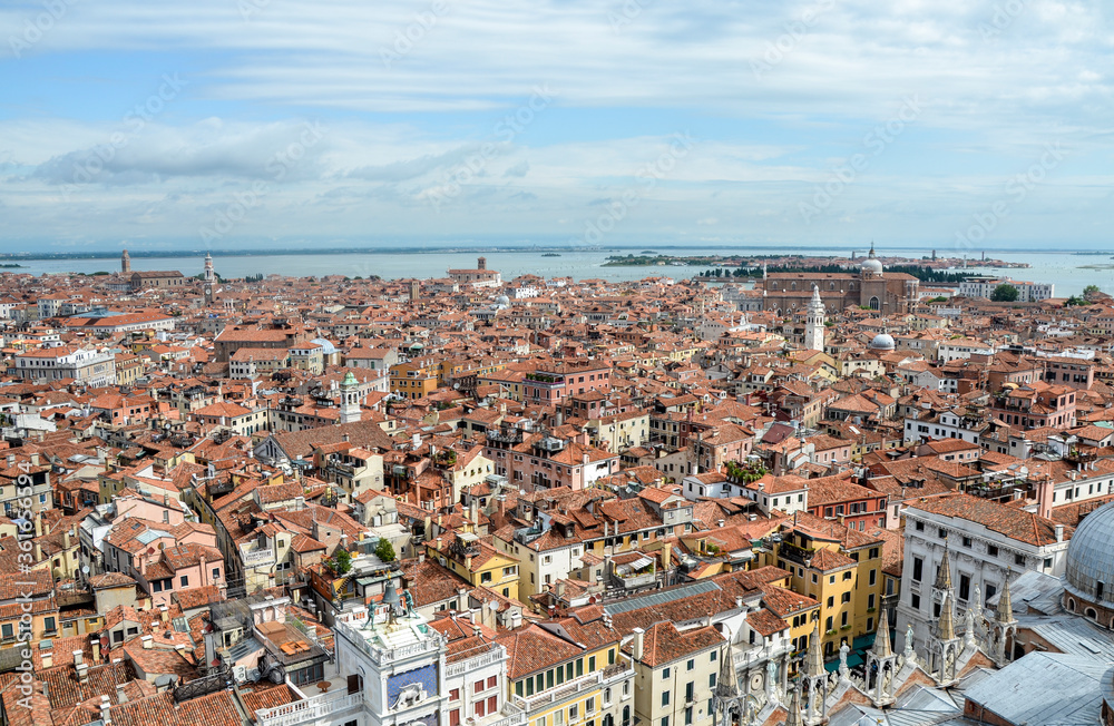 Top view to buildings with red-tile roofs, palaces, cathedrals and Mediterranean sea from San Marco tower in Venice, Italy