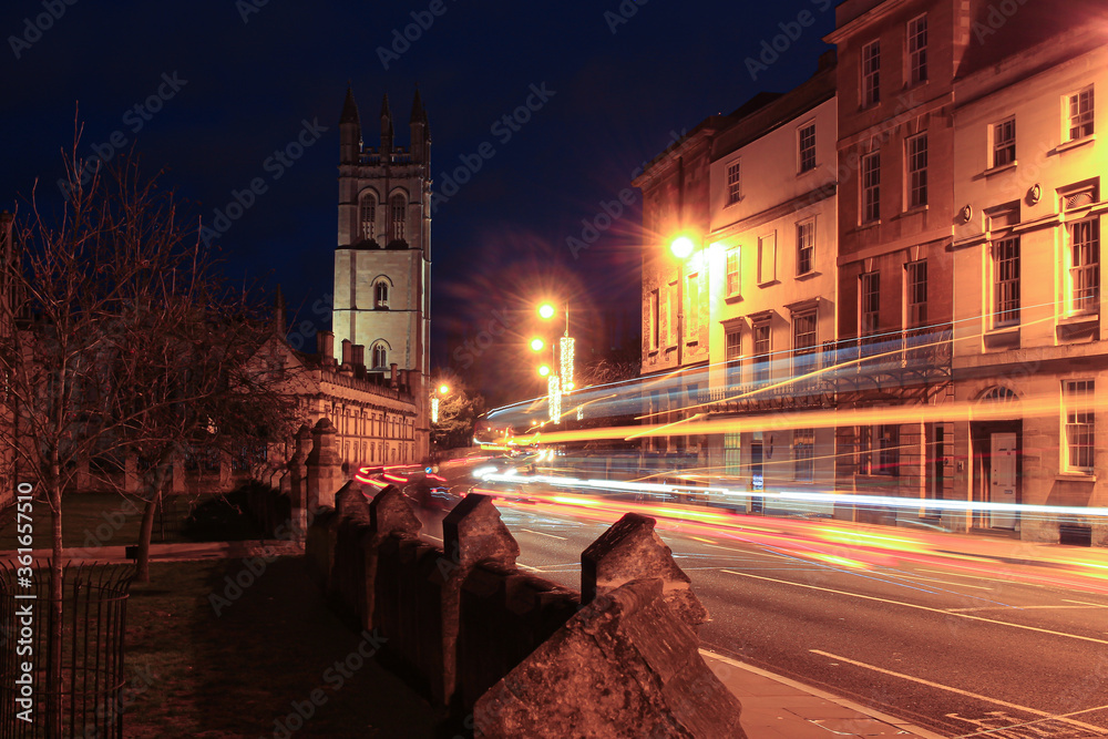 Streets of Oxford at night, floodlit tower with traffic trails in foreground
