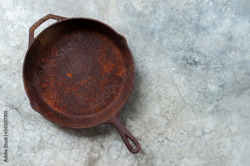 Obraz na plátne Old rusty round cast iron frying pan on   grey cement background, view from abov