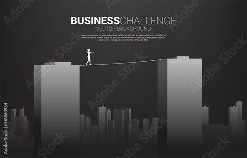 Silhouette of businesswoman walking on rope walk way across building.Concept for business risk and challenge in career path