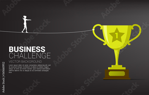 Silhouette of businesswoman walking on rope walk way to golden trophy .Concept for business risk and challenge.