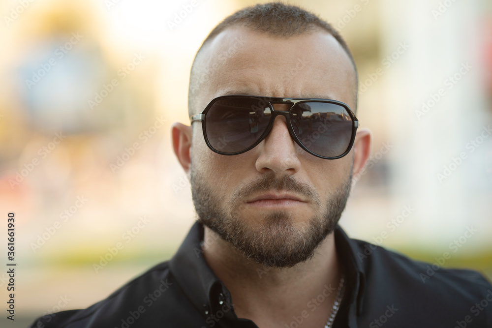 Confident handsome man in sunglasses and shirt over city background. Men's beauty, fashion. Outdoor portrait. Confident handsome man in sunglasses and shirt over city background. Men's beauty, fashion. Outdoor portrait.