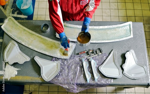 Installation of fiberglass: worker manually realizes a component in glass fiber for automotive use. Creating a spoiler for cars using a mold. View from above. photo