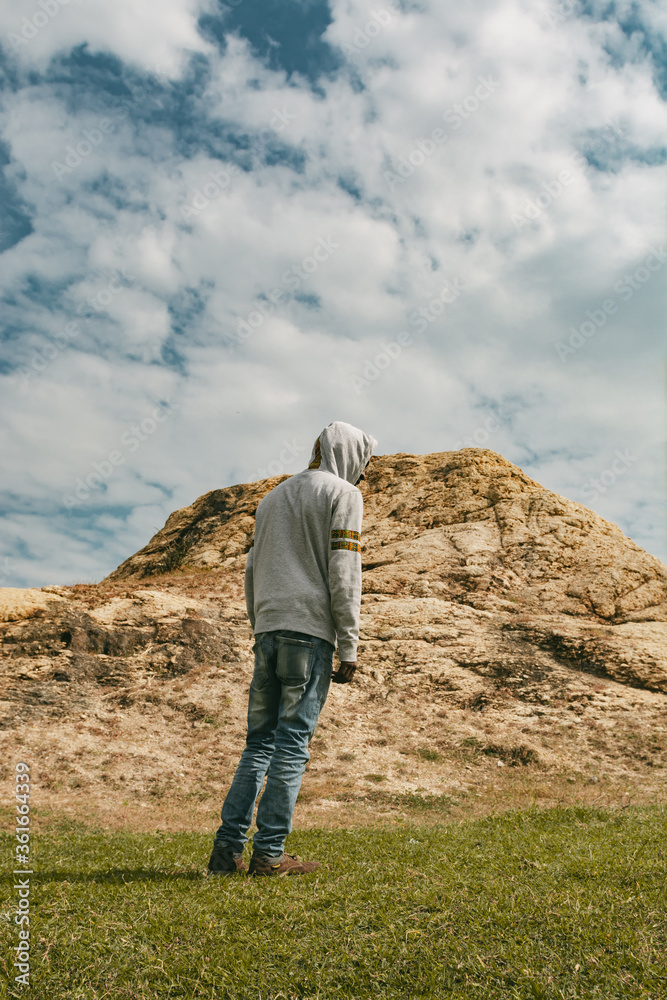Young black man walking towards a hill wearing a hoodie Young black man walking towards a hill wearing a hoodie