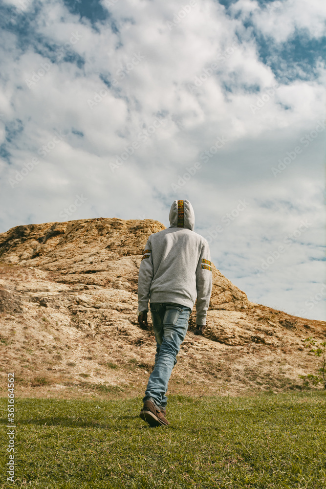 Young black man walking towards a hill wearing a hoodie Young black man walking towards a hill wearing a hoodie