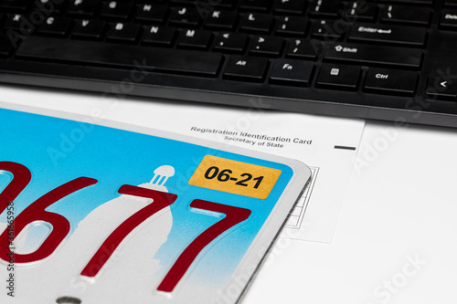 Vehicle license plate, renewal sticker, computer keyboard and registration card. Concept of state government automobile fees, transportation taxes, funding and online renewal