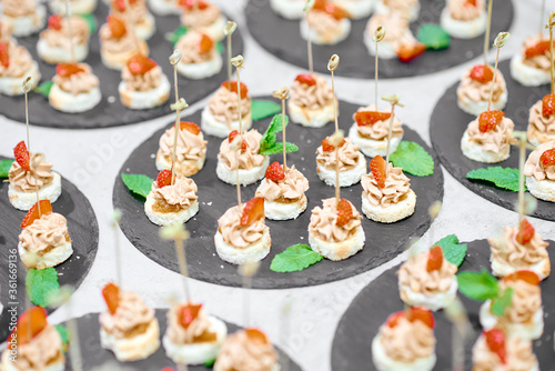 lots of canapes on black trays on a white table