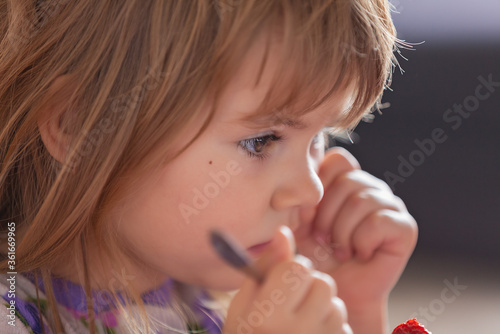 Adorable little girl in pajama eating strawberries at home