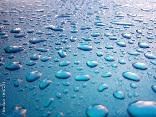 Dew drops on the roof of the blue car Use as background.