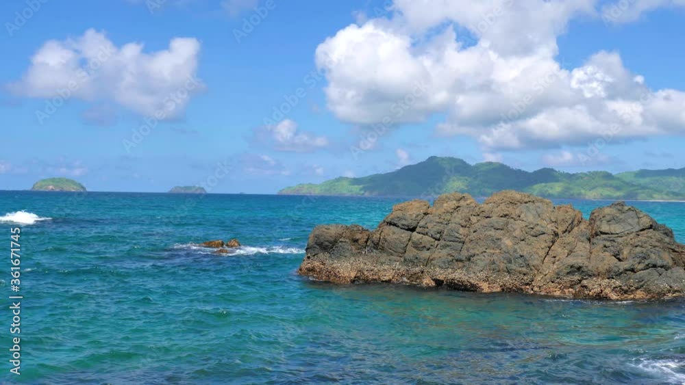 Waves beat against big rocks in the ocean with clear water. Concept of nature. Waves beat against big rocks in the ocean with clear water. Concept of nature.