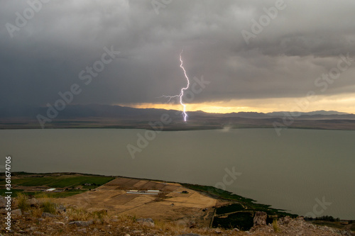 Lighting bolt striking the ground next to Utah lake during storm starting a fire