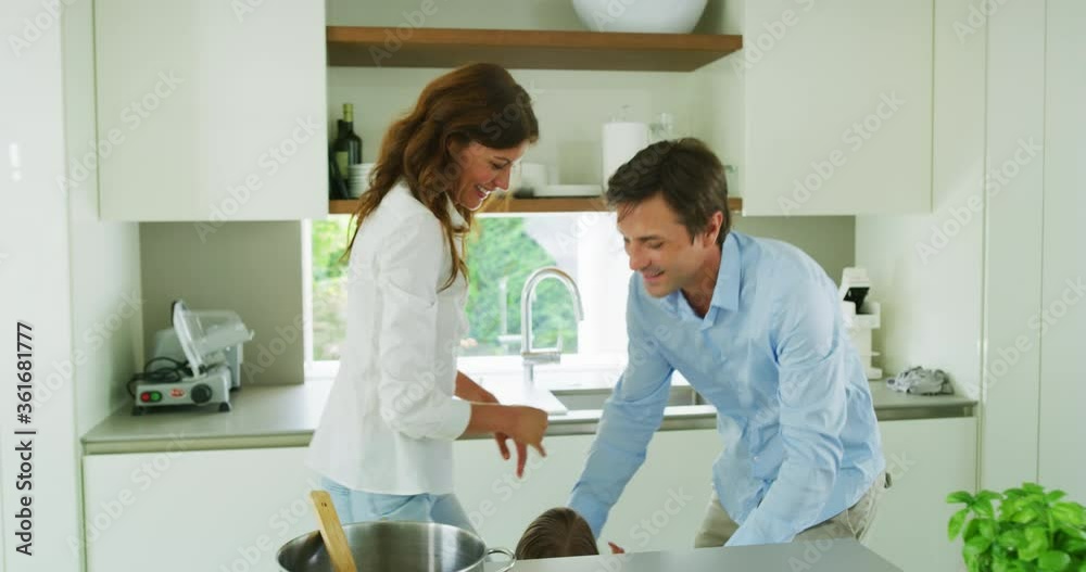 Authentic shot of lovely happy smiling parents and kids are enjoying their time and having fun to prepare a dinner together in a kitchen at home. Authentic shot of lovely happy smiling parents and kids are enjoying their time and having fun to prepare a dinner together in a kitchen at home.