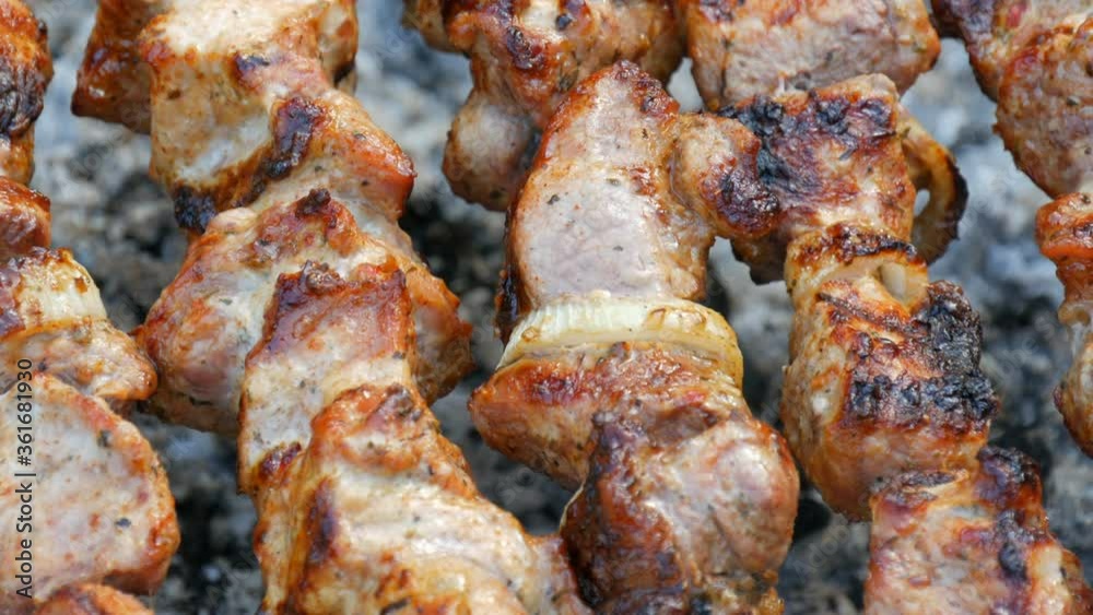 Sliced pieces of meat on a skewer. Pork skewers on the grill. Sliced meat with melting fat close up view in the garden of a country house Sliced pieces of meat on a skewer. Pork skewers on the grill. Sliced meat with melting fat close up view in the garden of a country house