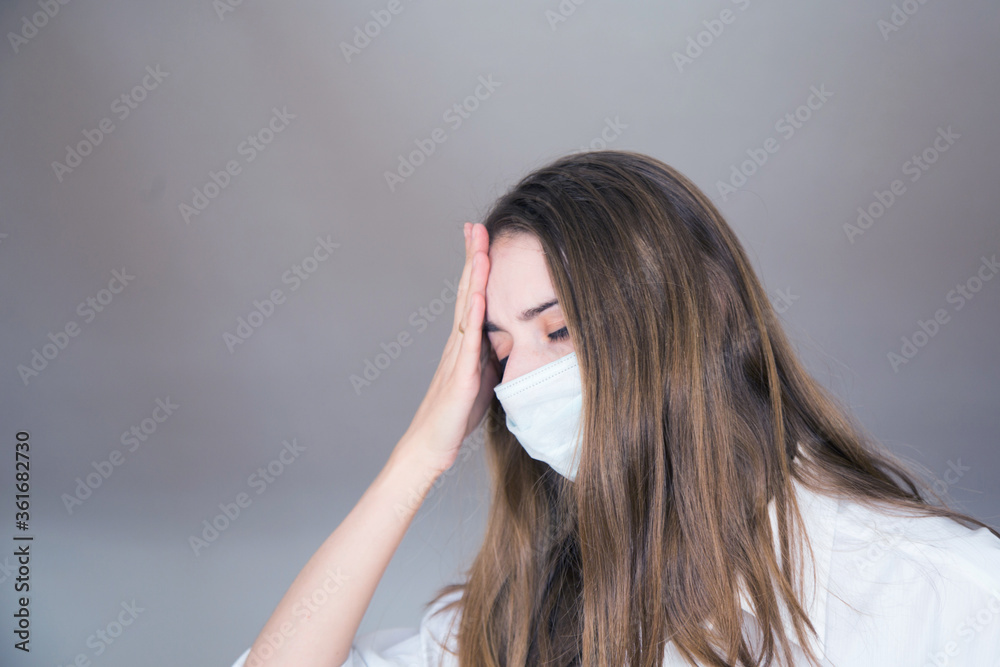 a woman in a medical mask on a white background in a medical mask. headache