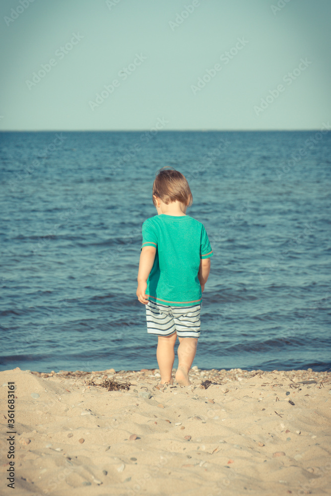 Baby boy walking and playing at summer beach. Vacation time and child development concept Baby boy walking and playing at summer beach. Vacation time and child development concept