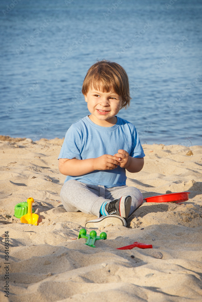 Smiling boy playing on sand at beach. Summer, vacation and relaxation time concept Smiling boy playing on sand at beach. Summer, vacation and relaxation time concept