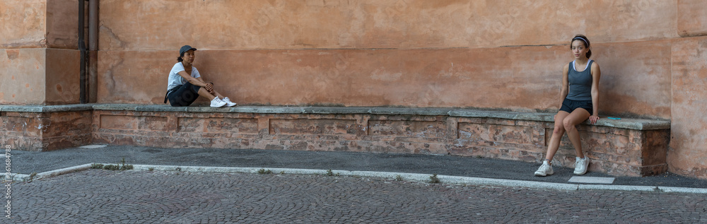 Mother and daughter sitting on brick bench in front of beautiful terracota plastered wall Mother and daughter sitting on brick bench in front of beautiful terracota plastered wall