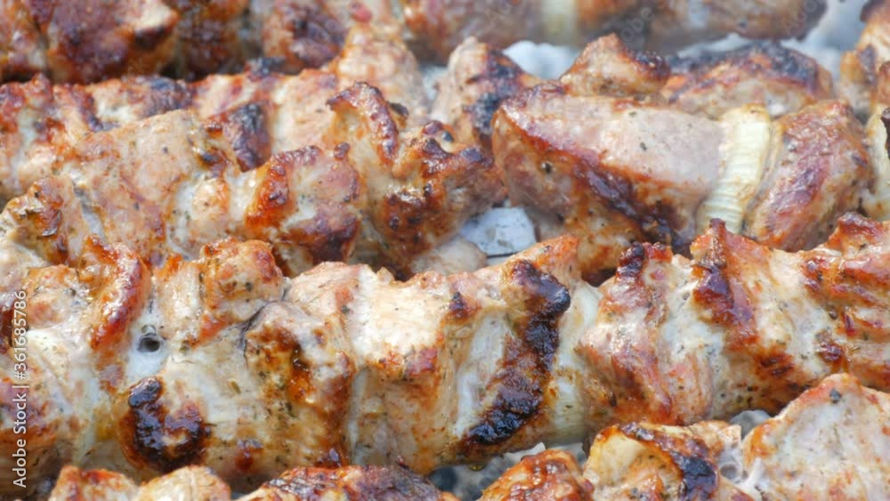 Sliced pieces of meat on a skewer. Pork skewers on the grill. Sliced meat with melting fat close up view in the garden of a country house Sliced pieces of meat on a skewer. Pork skewers on the grill. Sliced meat with melting fat close up view in the garden of a country house