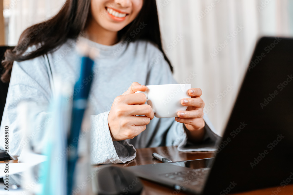 woman working on laptop and hold cup of coffee while sitting at working place. woman working on laptop and hold cup of coffee while sitting at working place.