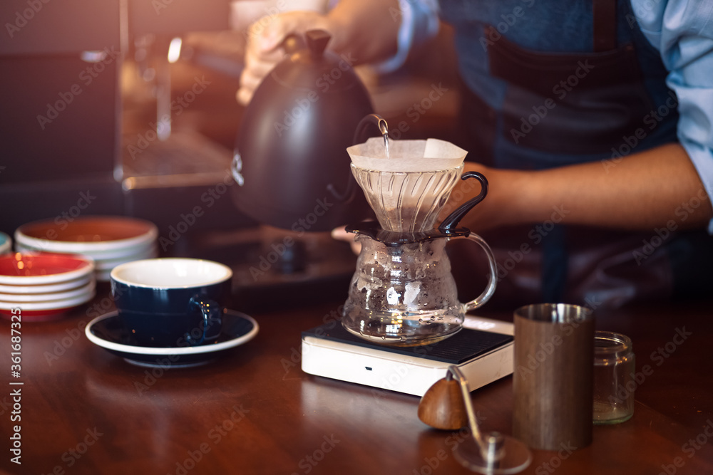 barista pouring boiling water from kettle to drip coffee maker. Stock