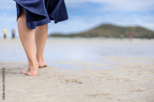 Woman barefoot walking on the beach at  summer along wave of sea water and sand. © Charnchai saeheng