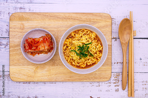 Spicy ramen (noddle) on a wooden board with a side dish (Kimchi).
