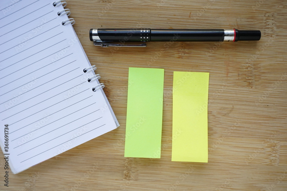note book, pen and sticky paper memo on the wooden table background