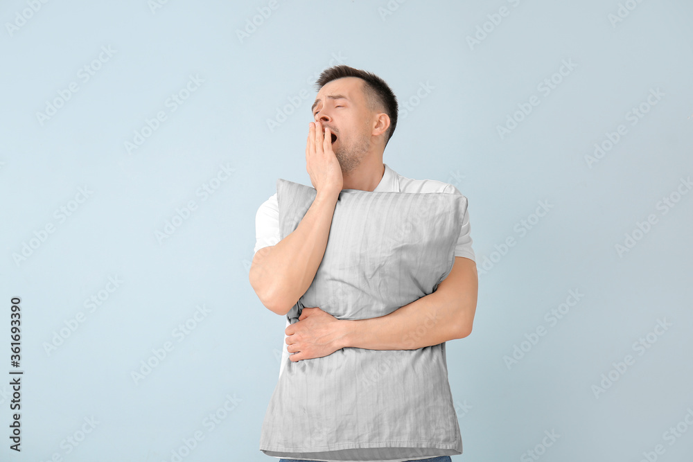 Tired man with pillow on color background. Concept of sleep deprivation Tired man with pillow on color background. Concept of sleep deprivation