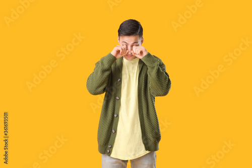 Fototapet Young man suffering from sleep deprivation on color background