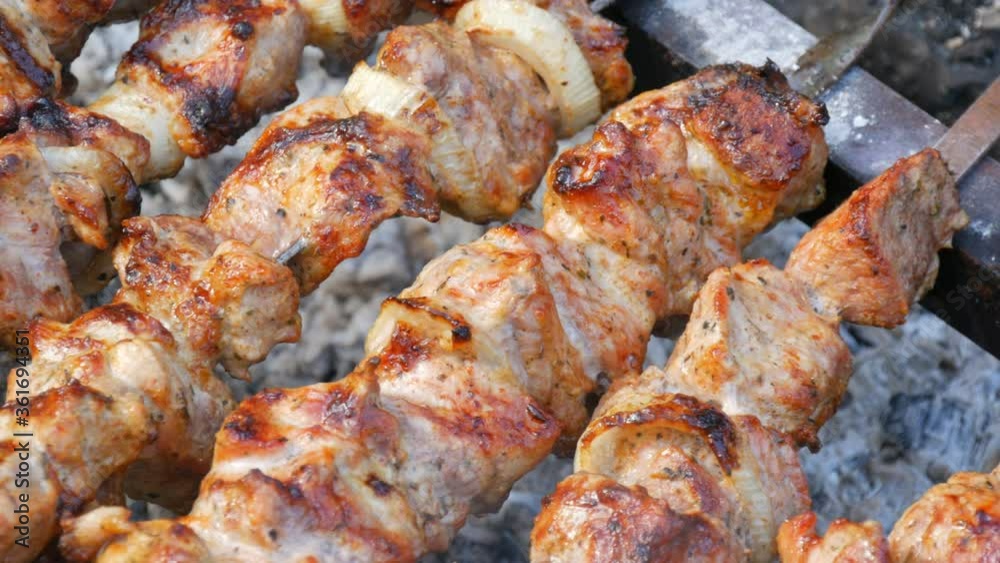 Sliced pieces of meat on a skewer. Pork skewers on the grill. Sliced meat with melting fat close up view in the garden of a country house Sliced pieces of meat on a skewer. Pork skewers on the grill. Sliced meat with melting fat close up view in the garden of a country house