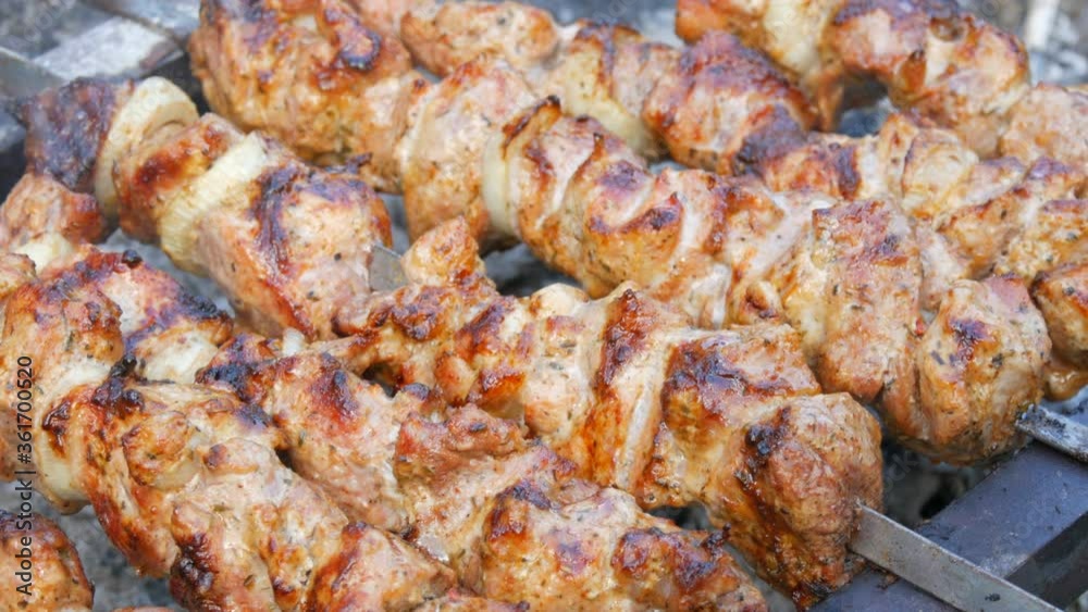 Sliced pieces of meat on a skewer. Pork skewers on the grill. Sliced meat with melting fat close up view in the garden of a country house Sliced pieces of meat on a skewer. Pork skewers on the grill. Sliced meat with melting fat close up view in the garden of a country house