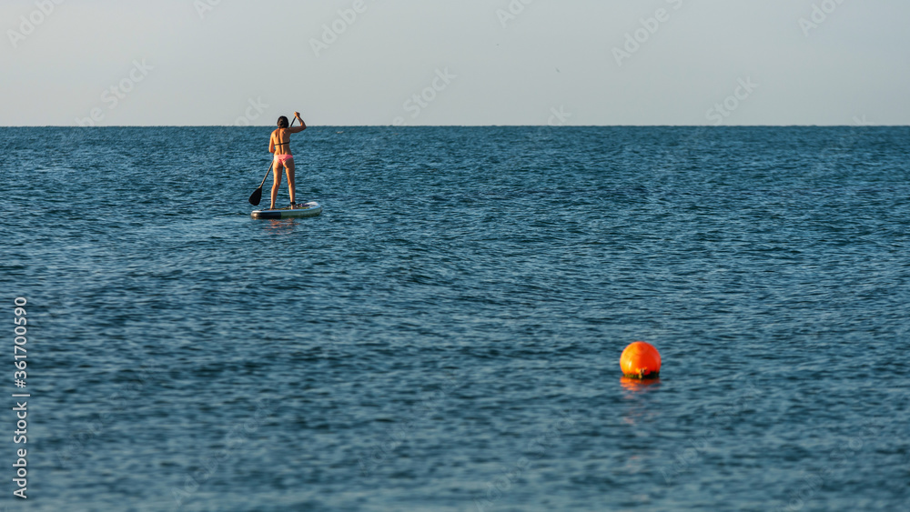 Bikini girl stand up sup paddleboarding on sea blue water panoramic landscape background