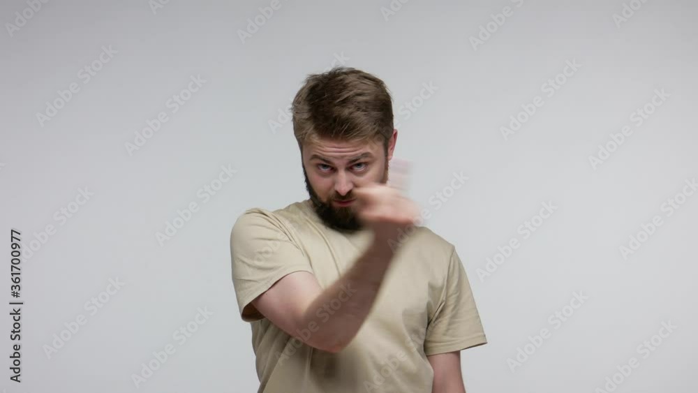 Crazy hooligan bearded man showing around his middle fingers, demonstrating protest with impolite rude gesture of disrespect, rejecting communication. indoor studio shot isolated on gray background Crazy hooligan bearded man showing around his middle fingers, demonstrating protest with impolite rude gesture of disrespect, rejecting communication. indoor studio shot isolated on gray background