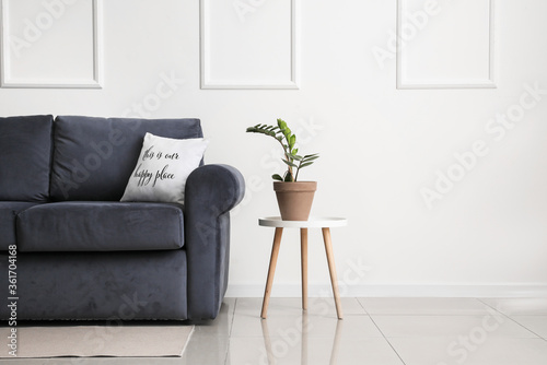 Obraz na plátně Stylish sofa and table with houseplant near light wall in room