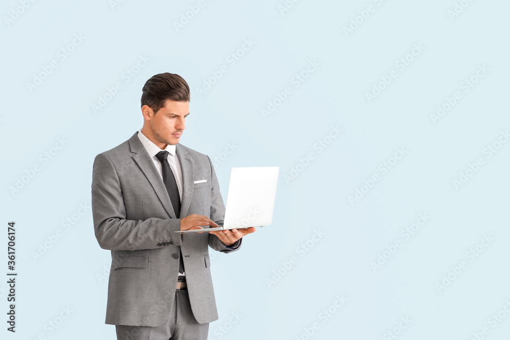 Young businessman in stylish suit and with laptop on color background Young businessman in stylish suit and with laptop on color background