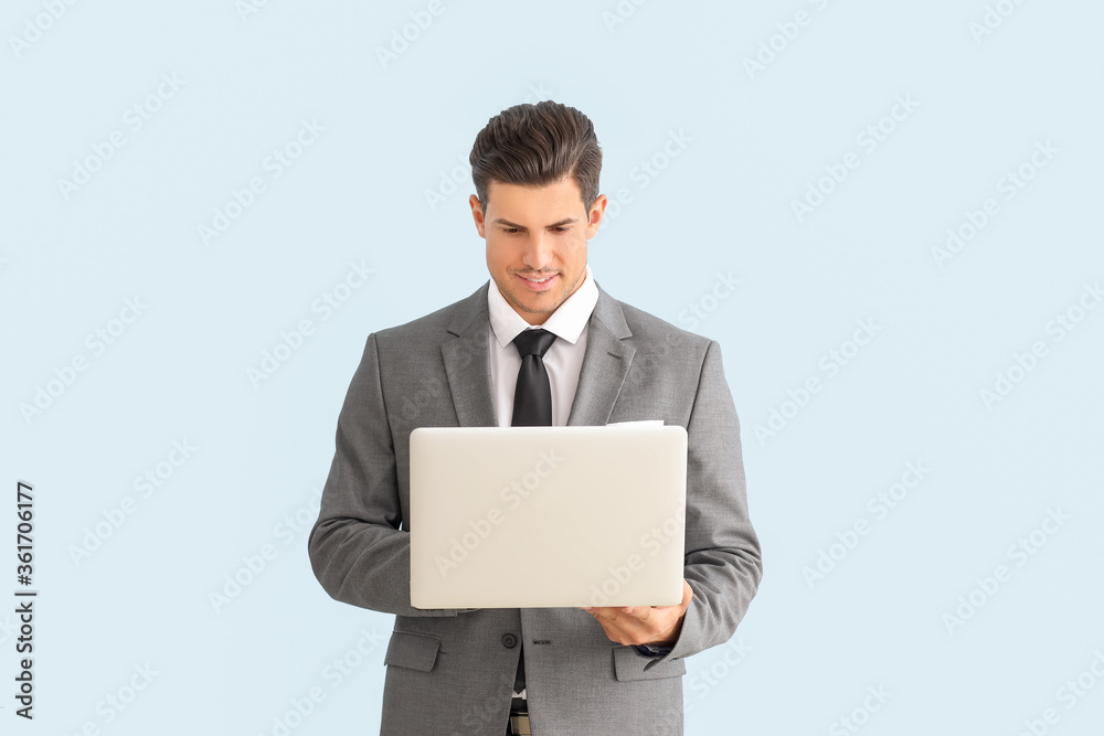 Young businessman in stylish suit and with laptop on color background Young businessman in stylish suit and with laptop on color background
