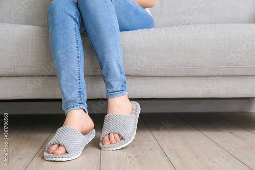 Woman in soft slippers sitting on sofa at home