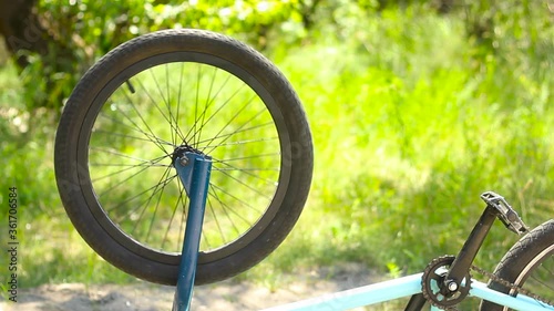 The spinning wheel of a bicycle. Inverted blue bmx bike with a spinning wheel in the park.