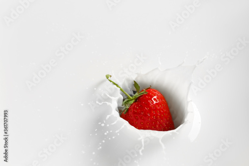 Falling of fresh strawberry into milk