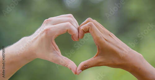 Black and white hands touch a heart - a symbol of anti-racism.
