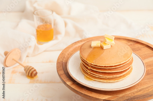 Tasty pancakes with honey and butter on table