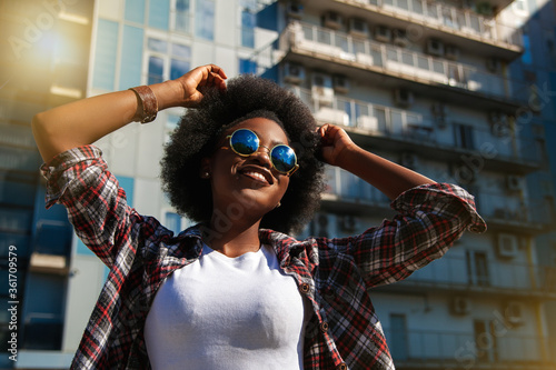Positive emotions and people concept  young happy black african american female with curly black hair. Over city background. 
