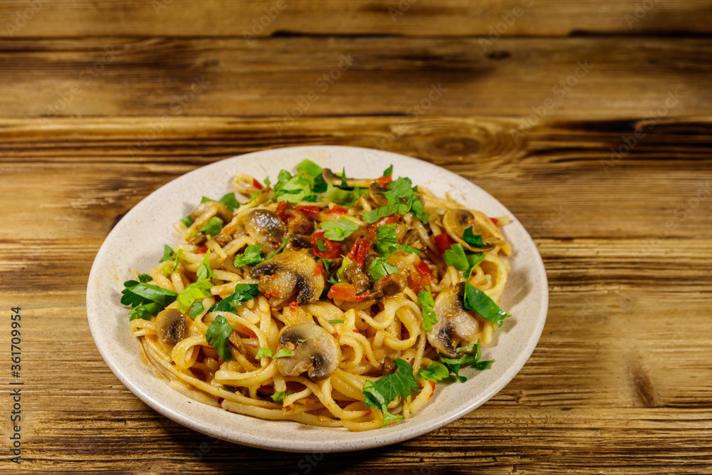 Pasta with mushrooms and tomato sauce on wooden table Pasta with mushrooms and tomato sauce on wooden table