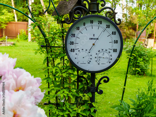 Summer heat. The antique thermometer on a background of green grass surrounded by flowers
