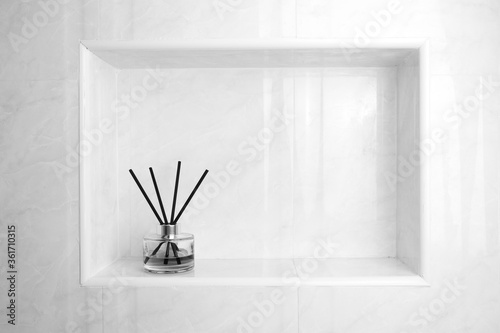 black and white photo of luxury glass aroma scent reed diffuser bottles with yellow oil are displayed in the nice white toilet bahtroom to creat relax and cleaness ambient © Sutthisak