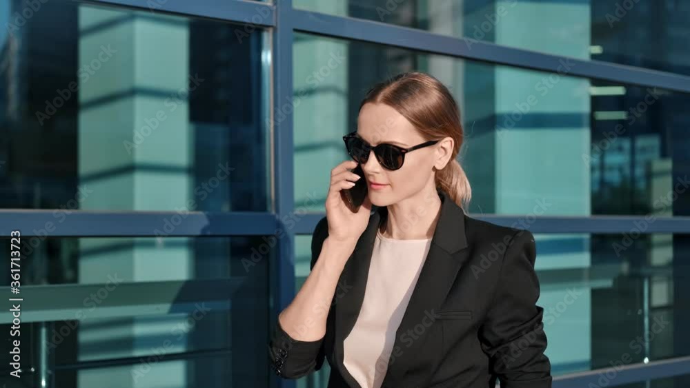 Stylish blonde lady boss walk outdoor at downtown talking use smartphone. 4k Dragon RED camera Stylish blonde lady boss walk outdoor at downtown talking use smartphone. 4k Dragon RED camera